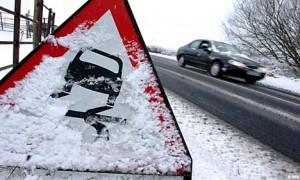 Car driving on the road approaching a danger sign indicating frozen roads